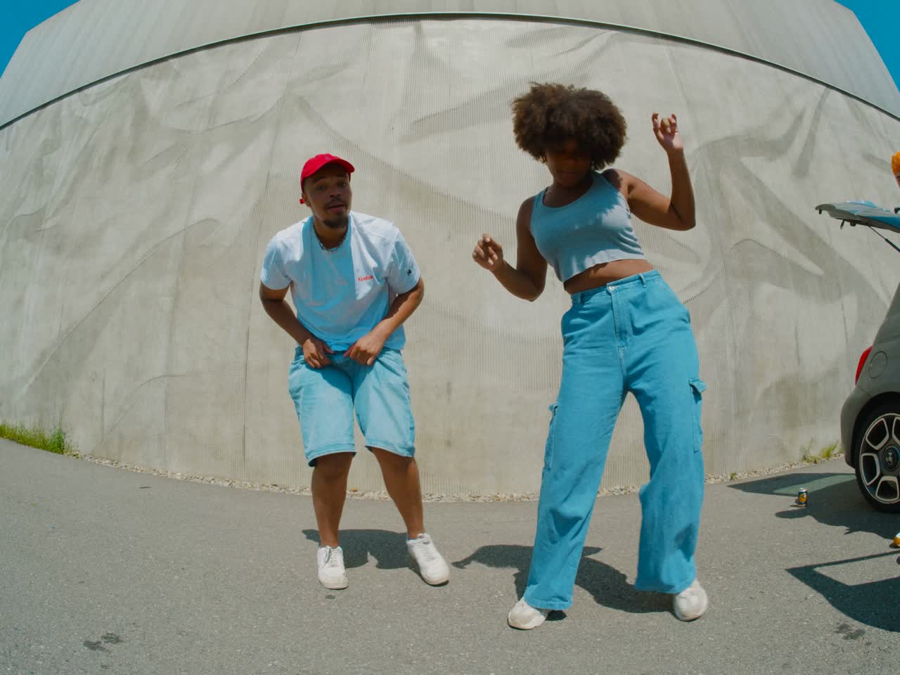 Two dancers performing in front of a curved wall