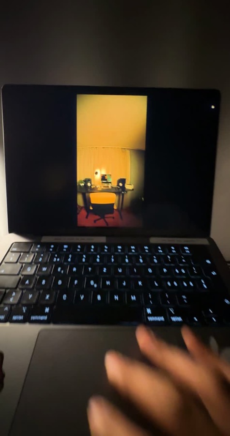 Hands typing on a laptop with a video on screen